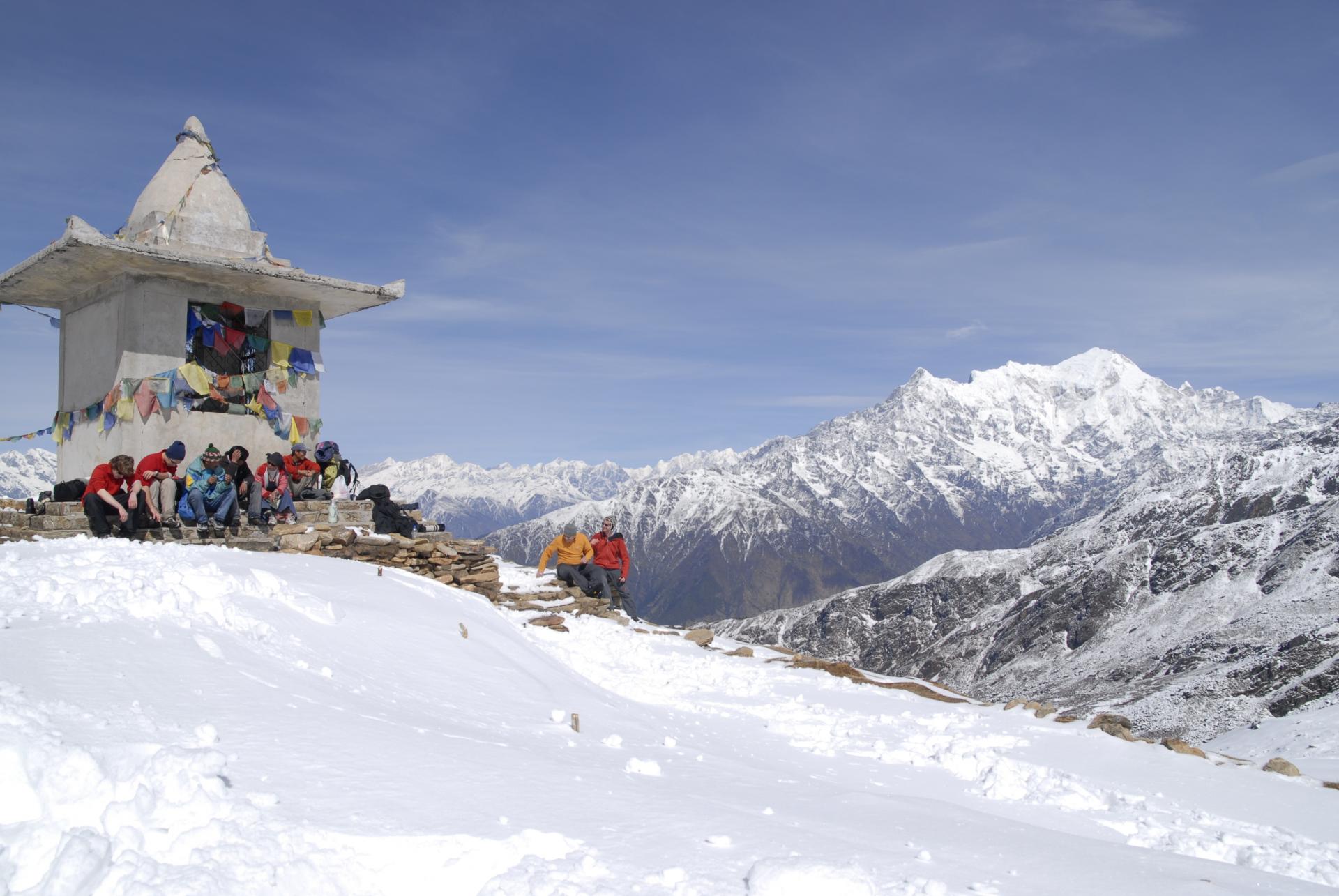 Langtang, Gosainkund and Helambu Trek - a few people sit around a hill top temple with flags surrounding it and mountains all around them