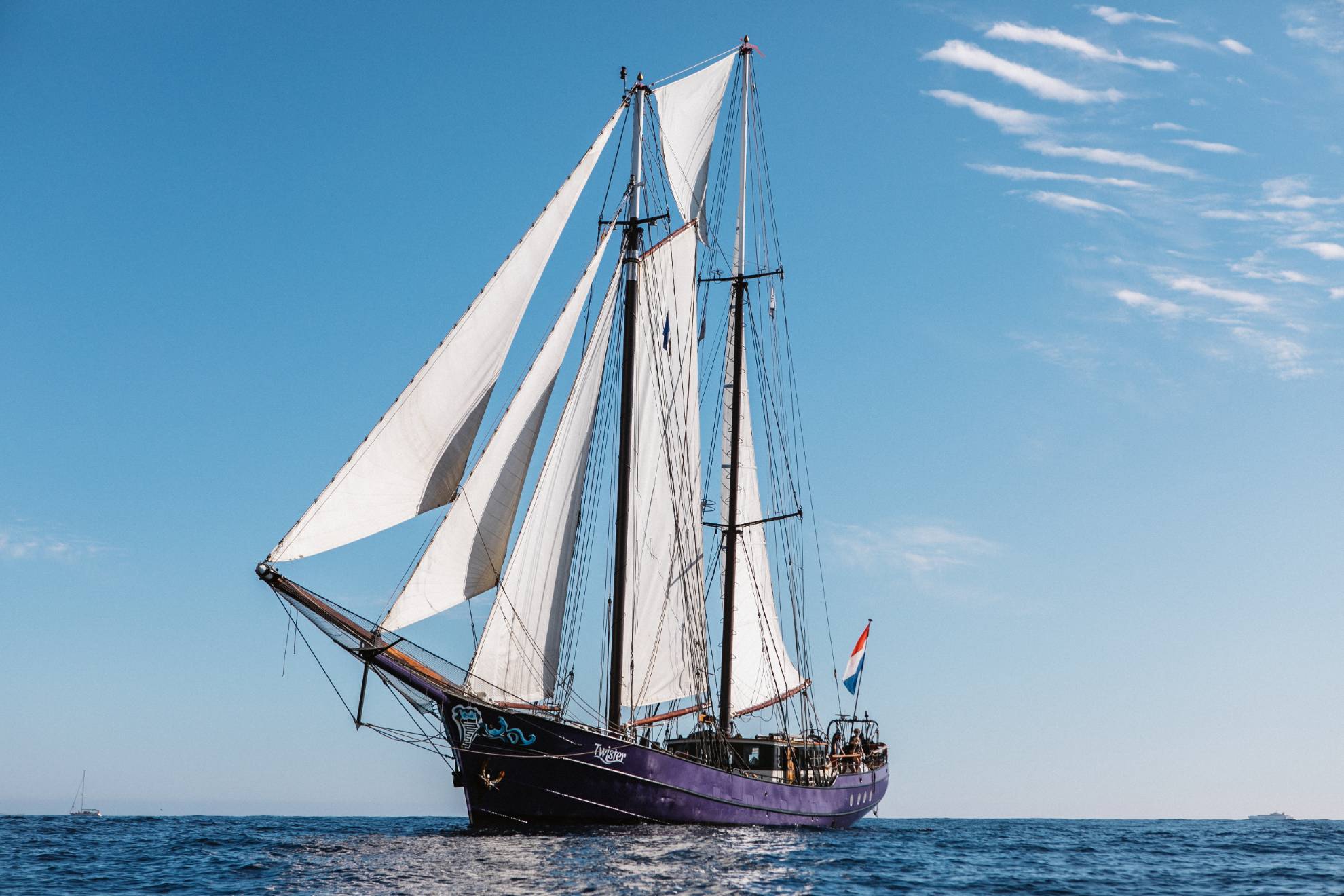 A tall ship with is purple with it's large white sails unfurled