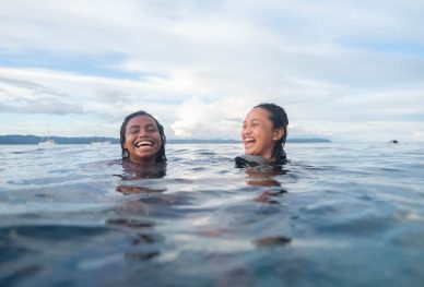 Two women treading water laugh at each other