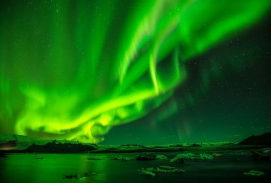 A green Aurora shines brightly against a dark sky